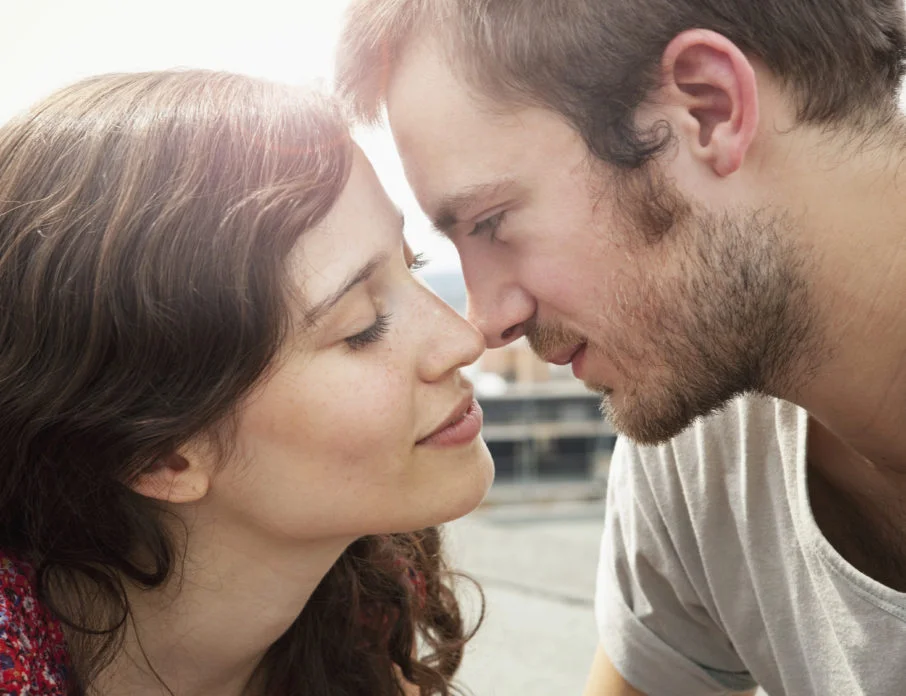 Couple in an exclusive relationship looking closely into each other's eyes while preparing to kiss.