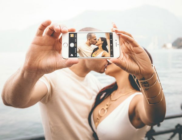 A couple who took these online dating tips to hear and are kissing while taking a selfie.