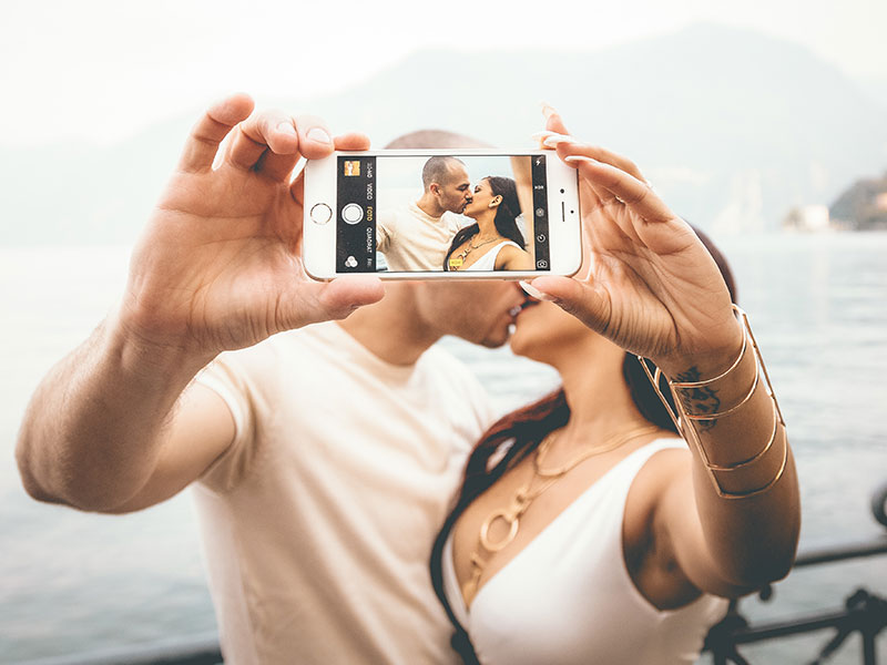 A couple who took these online dating tips to hear and are kissing while taking a selfie.