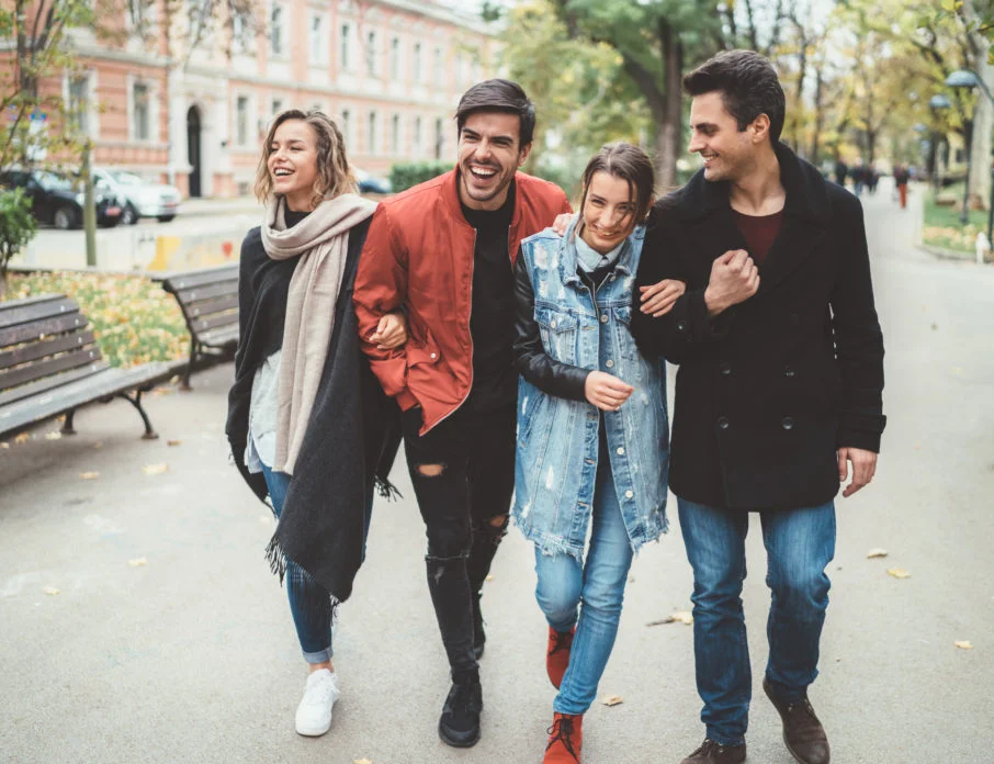 Two happy couples walking down the street together and laughing while trying out some of the best double date ideas.