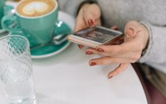 Woman using mobile phone while having a coffee to check is Bumble free?