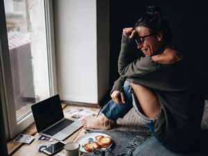 attractive woman laughing in front of laptop speaking with man who knows how to start a conversation with a girl online