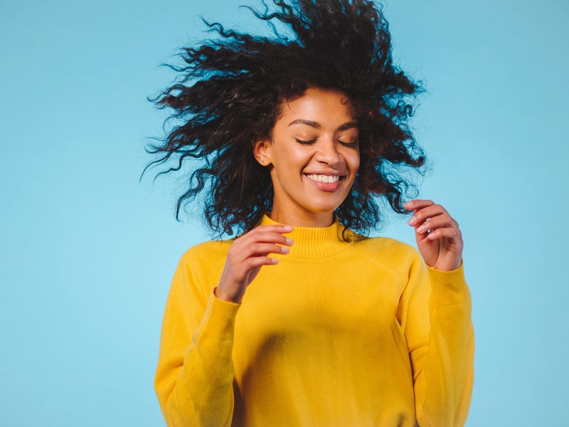 attractive young women in yellow sweater dancing in front of blue wall after reading positive break up quotes