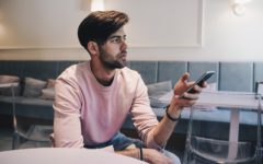 attractive young man on his mobile phone in a coffee shop thinking about how often to text a girl