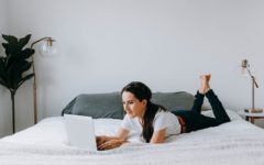 woman lying on bed using laptop to browse the best dating sites for women
