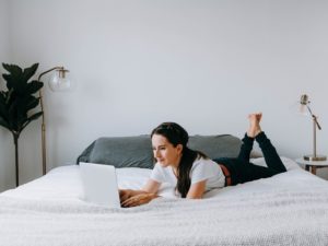 woman lying on bed using laptop to browse the best dating sites for women