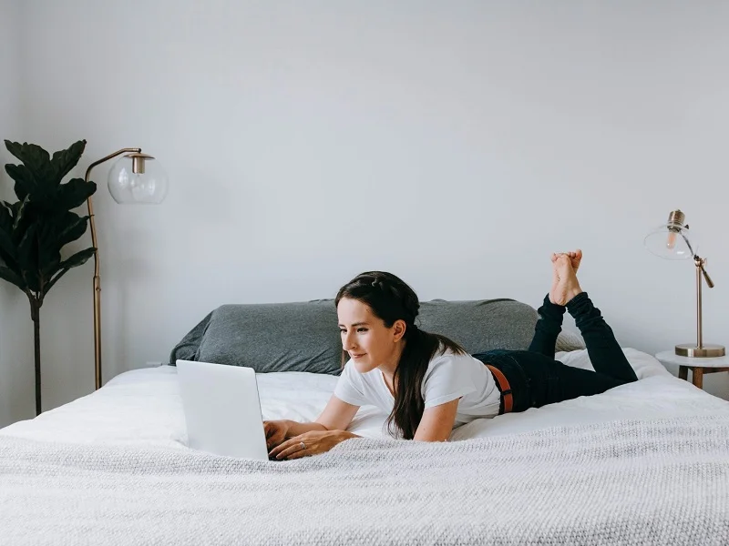 femme allongée sur le lit à l'aide d'un ordinateur portable pour parcourir les meilleurs sites de rencontres pour femmes