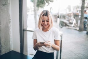 woman laughing after getting flirty text messages for her