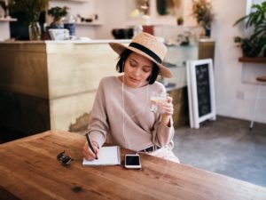 attractive lady sitting at table working out how to use dating profile headlines to attract guys