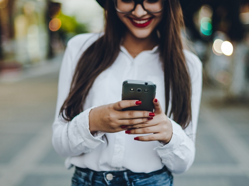 Attractive young woman on mobile phone using her good dating profile