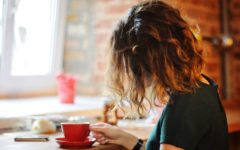 woman sitting in cafe drinking coffee wondering why am I single?