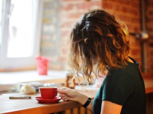 woman sitting in cafe drinking coffee wondering why am I single?