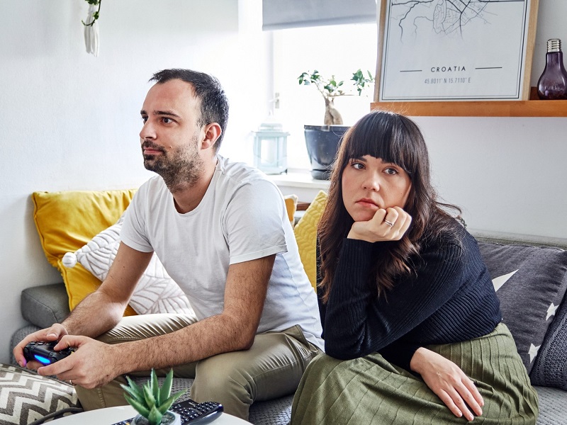 unhappy couple sitting on the sofa with woman experiencing the fawn response