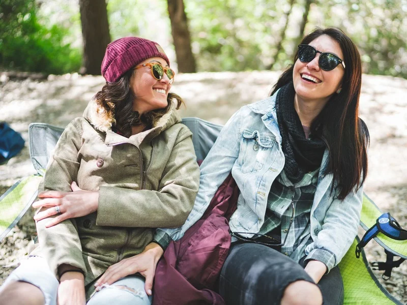 two women who met on one of the best bisexual dating apps sitting outside and laughing