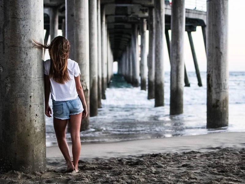 woman standing under a pier thinking about toxic relationship definitions