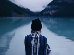 woman sitting alone by a lake considering the characteristics of an unhealthy relationship
