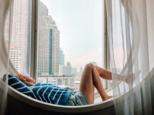 woman sitting on window sill looking over sitting thinking about going back to an ex