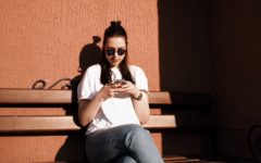 woman sitting on a bench typing her best hinge answers on her mobile phone