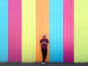 a man standing in front of colorful wall holding phone trying to decide what to text a girl he just met