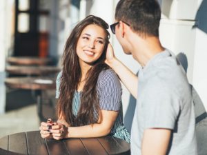 man sitting at cafe with attractive woman showing how to get a girlfriend