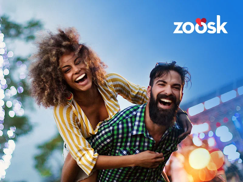 attractive couple who met on Zoosk dating laughing outside with her on his back