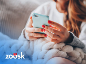 A woman holding her phone using Zoosk mobile