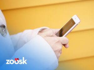 Woman holding mobile phone using the Zoosk app