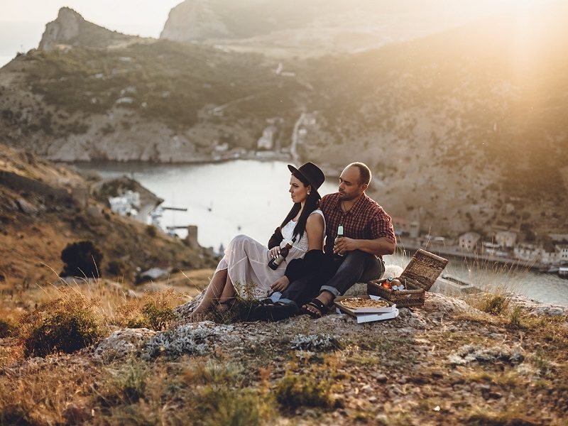couple on an outdoor date having a picnic at sunset