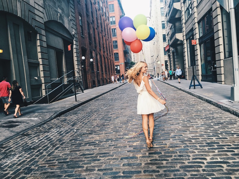 lady walking in the street with balloons showing the perks of dating in your 30s as a woman