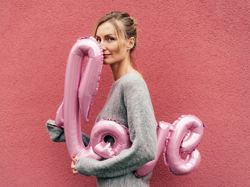 Woman smiling with love balloon on Valentine's Day 2021