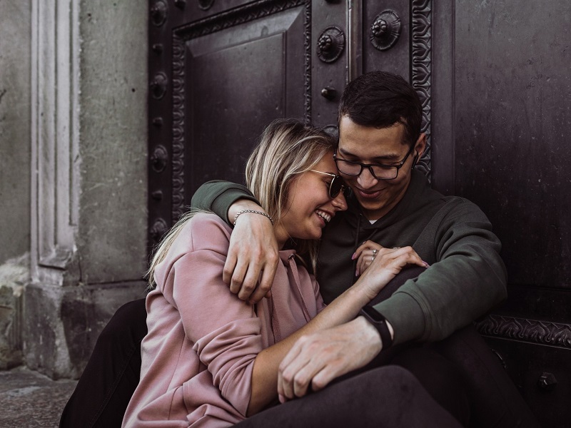 happy couple who love each other laughing outside sitting on a step