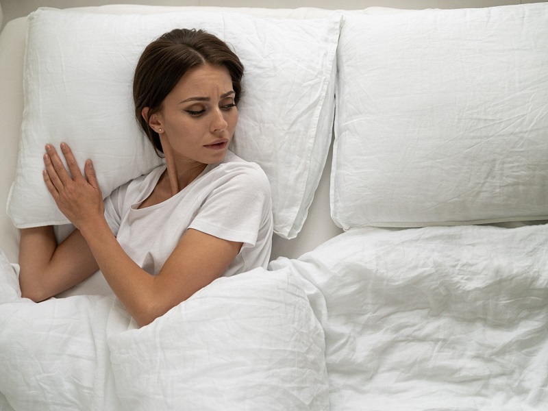 woman lying alone in bed looking sad after facing common relationship problems