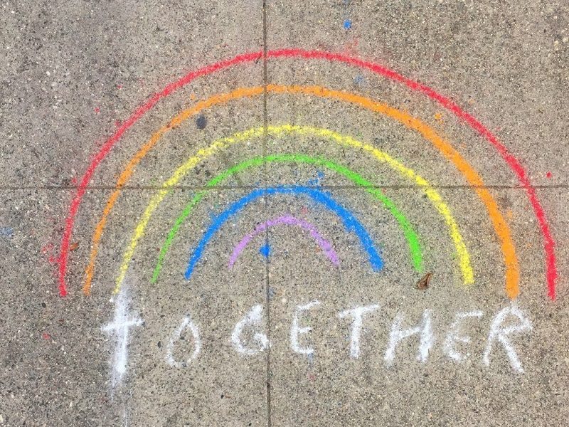 rainbow written in chalk with the word together written on the sidewalk for Pride Month.