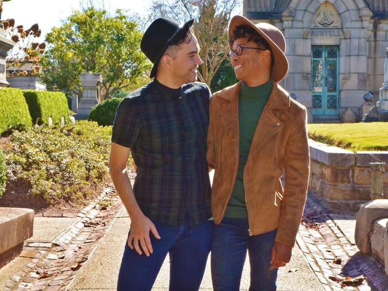happy gay couple holding hands outside and laughing