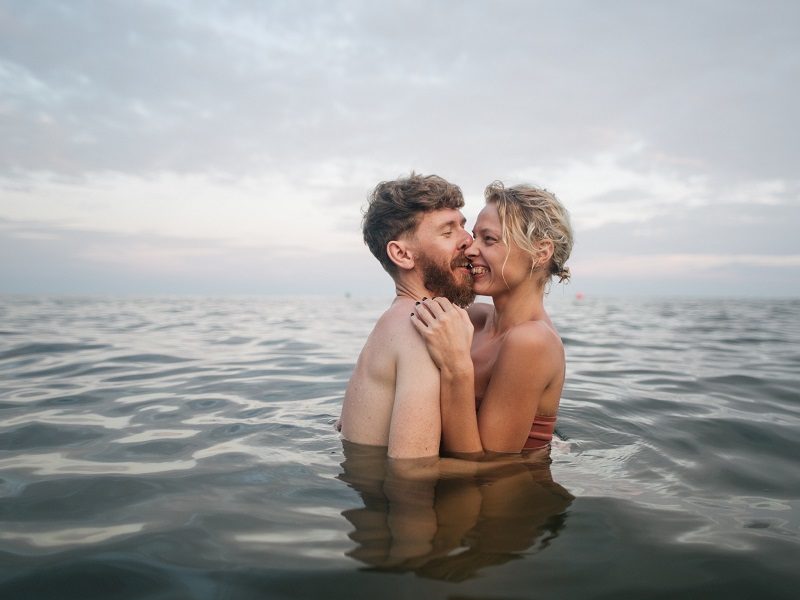 laughing couple standing in the ocean holding each other