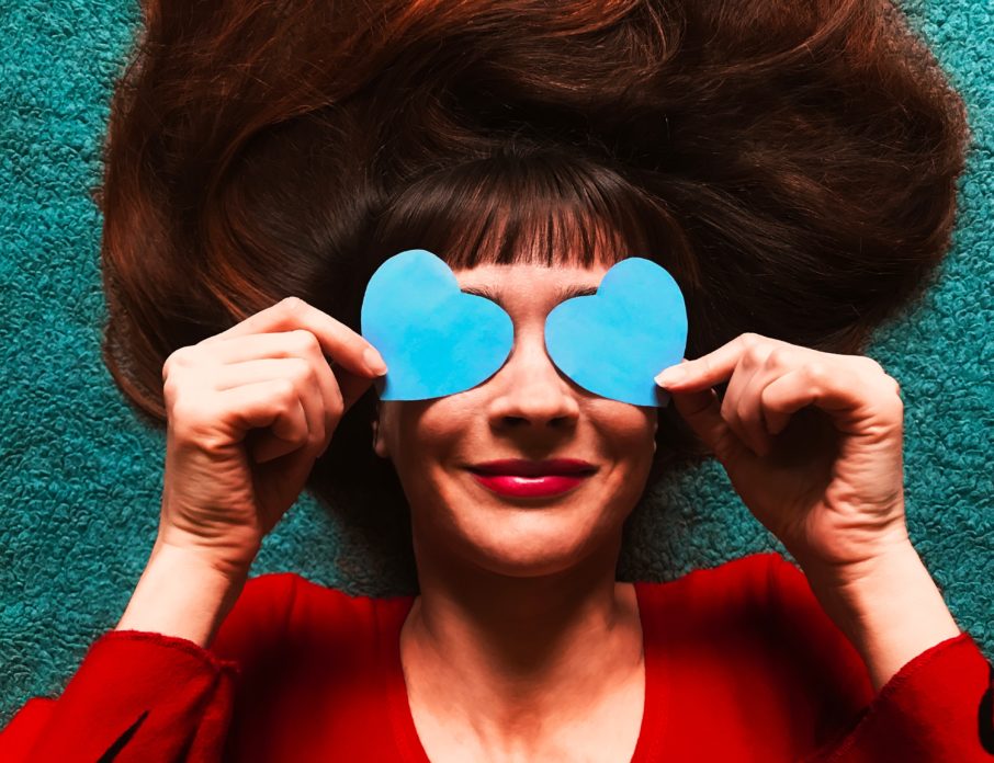 woman's face with heart sunglasses smiling on blue background