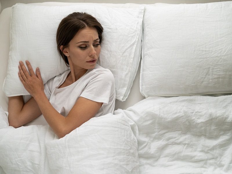 woman lying alone in bed looking sad