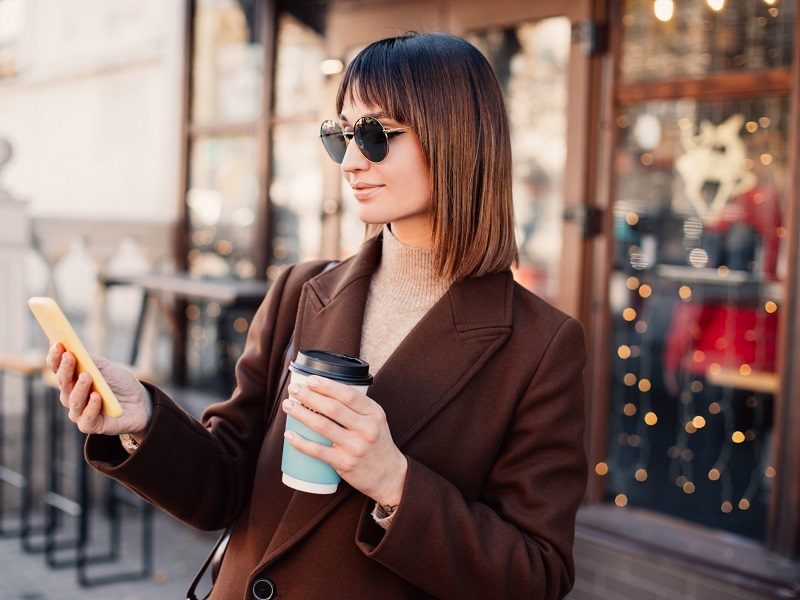 woman drinking a coffee using her mobile phone