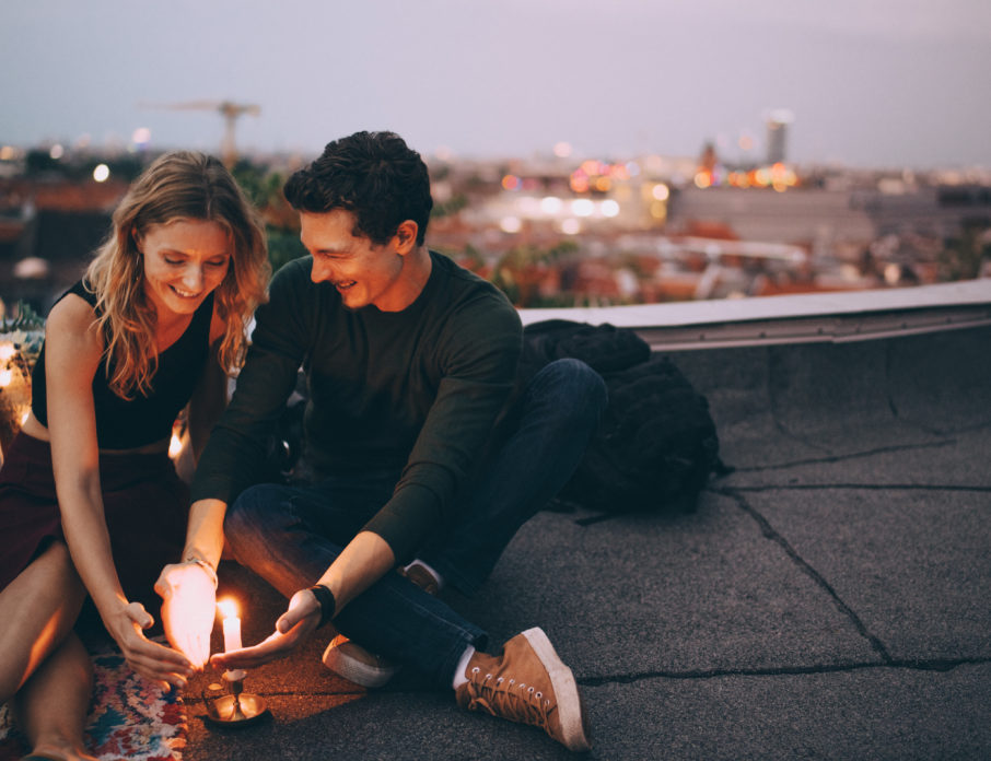 Happy, smiling couple sitting around a candle while on a date at a romantic place to visit.