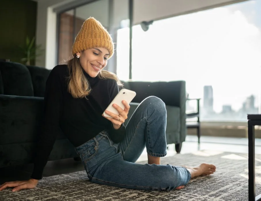 Smiling woman using smartphone at home during Dating Sunday.