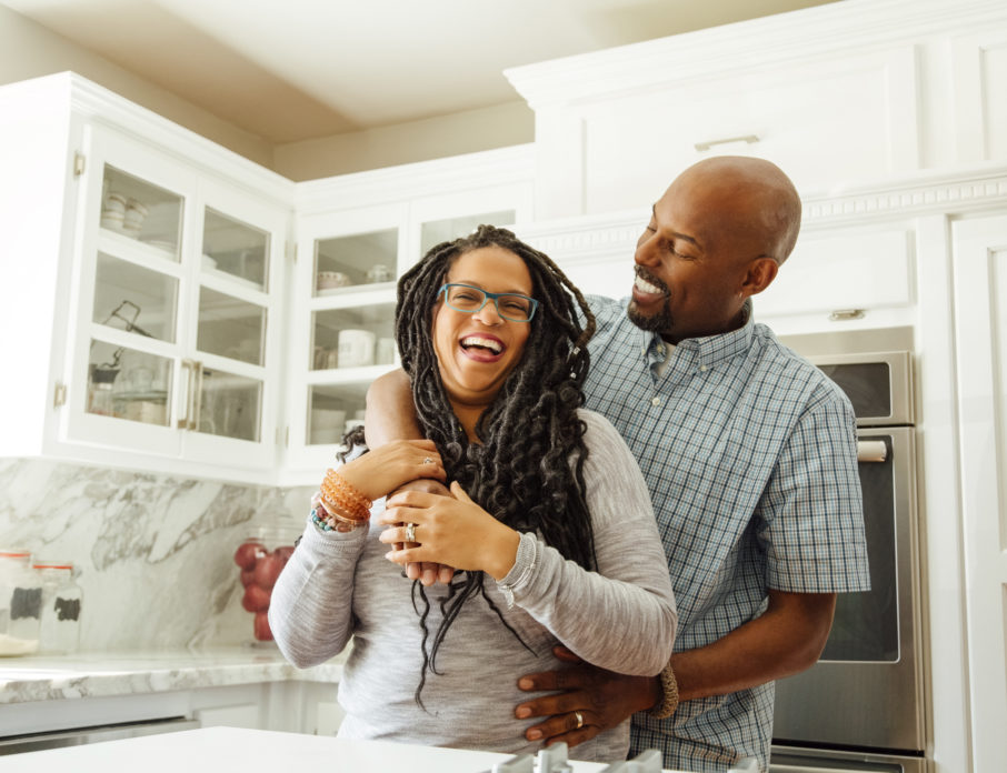 Happy, smiling couple, laughing and embracing each other in a kitchen.