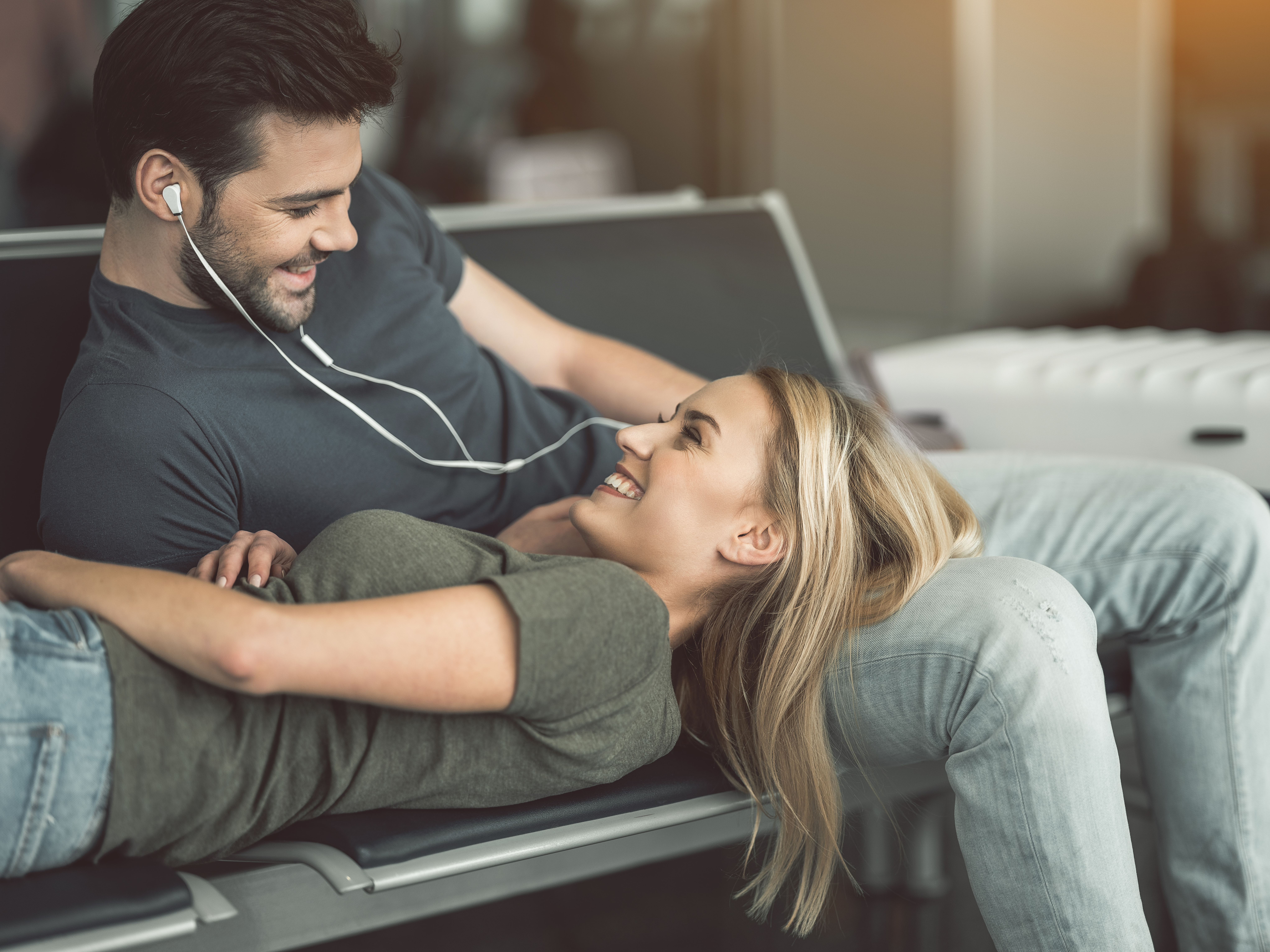 Happy, romantic couple relaxing on safe with earphones in and listening to some classic love songs.