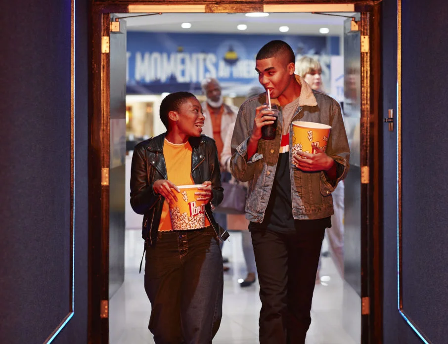 Happy young couple holding popcorn in a movie theatre after watching on Oscar-winning romance movie.