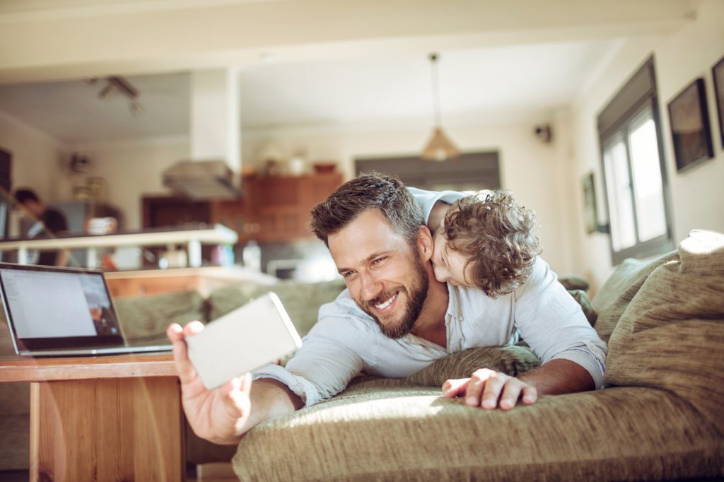 single dad online dating holding phone with son laughing on his back