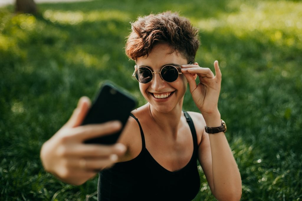 smiling single woman taking selfie outside for lesbian dating sites