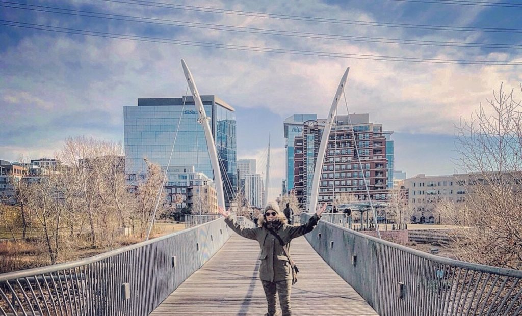 single woman smiling in front of Millennial bridge in Denver