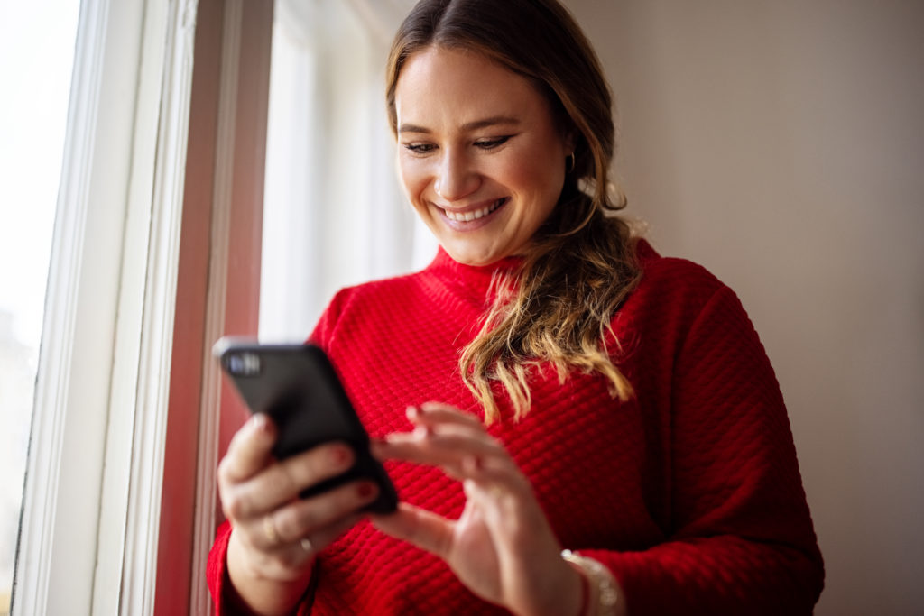 Happy woman on her phone smiling while online dating in San Jose.