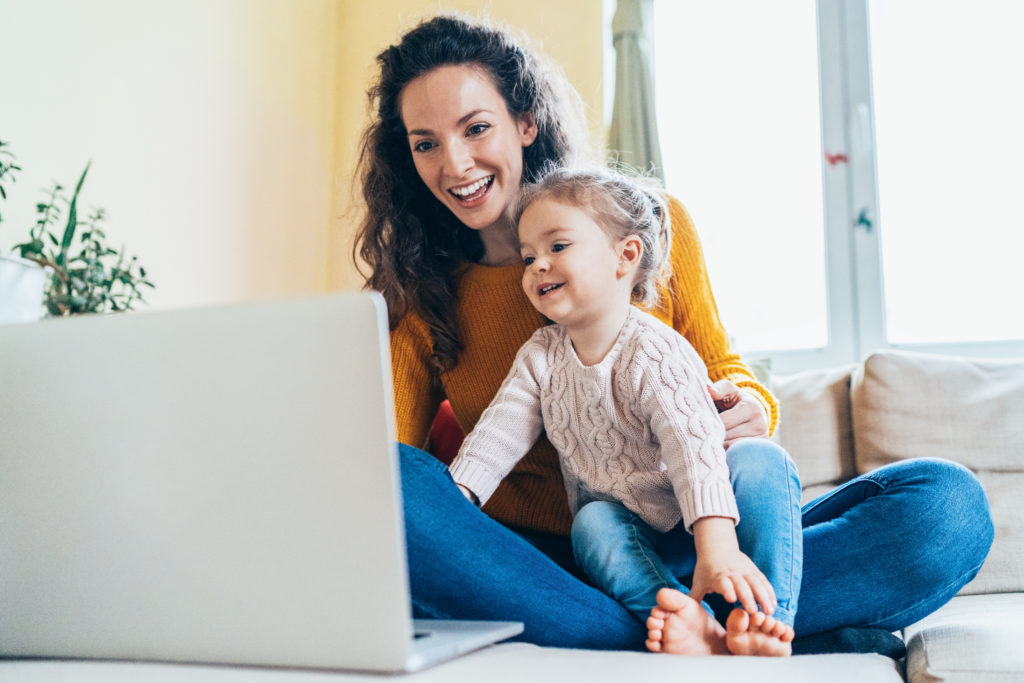 Mother and young daughter smiling together and looking at laptop while connecting with singles online who are looking to date a single mom.