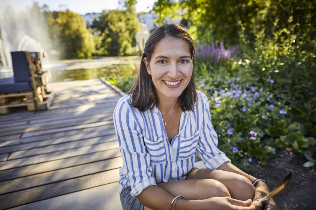 Woman in her 40s sitting outdoors and looking towards the camera and smiling while dating in New Jersey.
