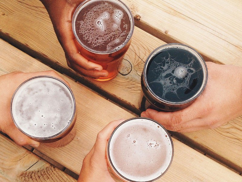 Couples hands with beers on a table while they're on a double date.